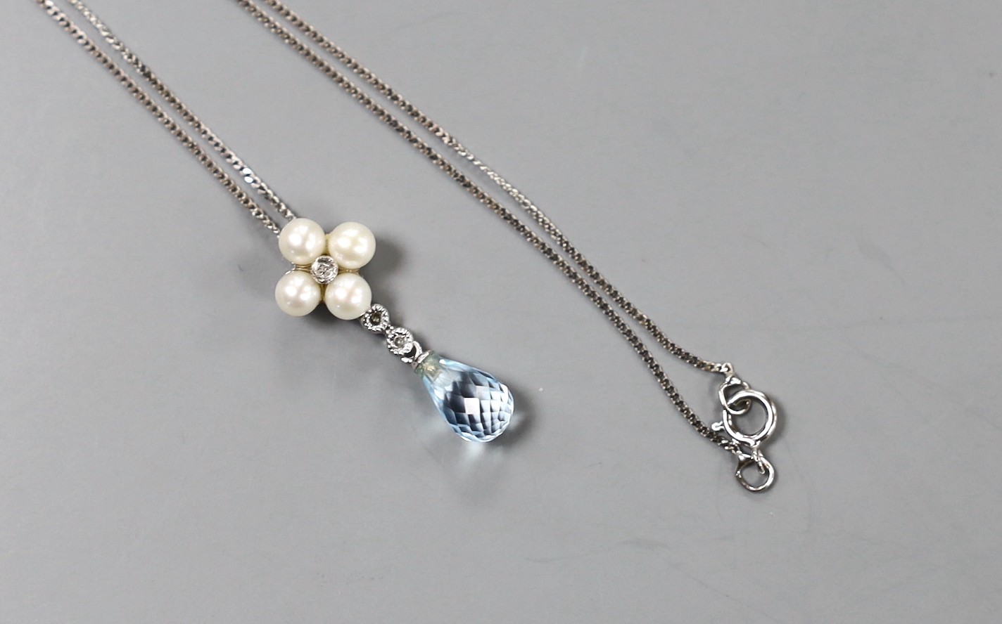 A modern 9k white metal, blue topaz, cultured pearl and diamond cluster set drop pendant, 23mm, on a 375 fine link chain, 46cm, gross weight 2.2 grams.